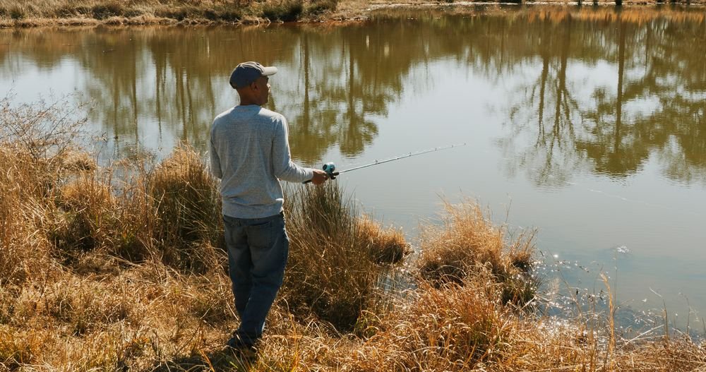 A man fishing at the edge of a pond