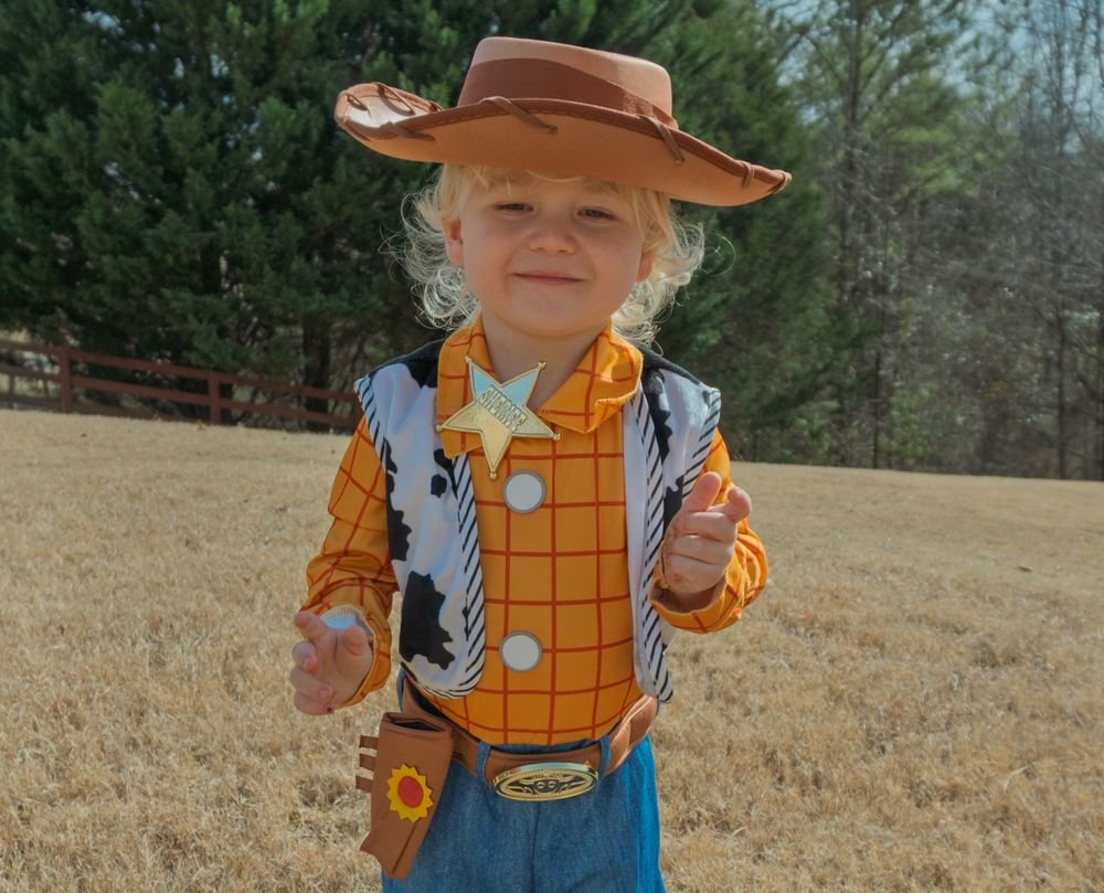 A small child in a cowboy costume in a field
